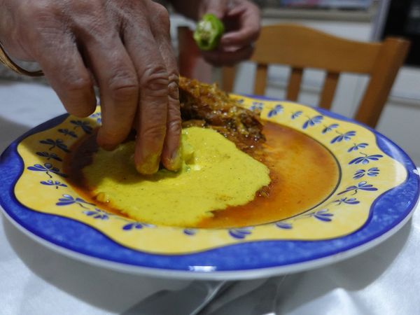 הווצ'ארה צהובה בצלחת, ויד טובלת בה ירק